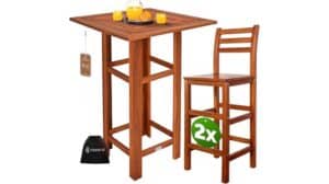 Ein hölzerner Casaria-Bartisch mit zwei passenden Barhocker-Set-Stühlen, einem Glaskrug und Tassen mit Orangensaft auf dem Tisch und einer schwarzen Tasche auf dem Boden.